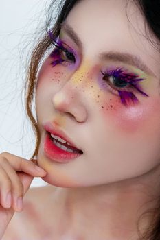 Close-up portrait showcasing creative colorful makeup with bold eyeshadow and artistic detail.