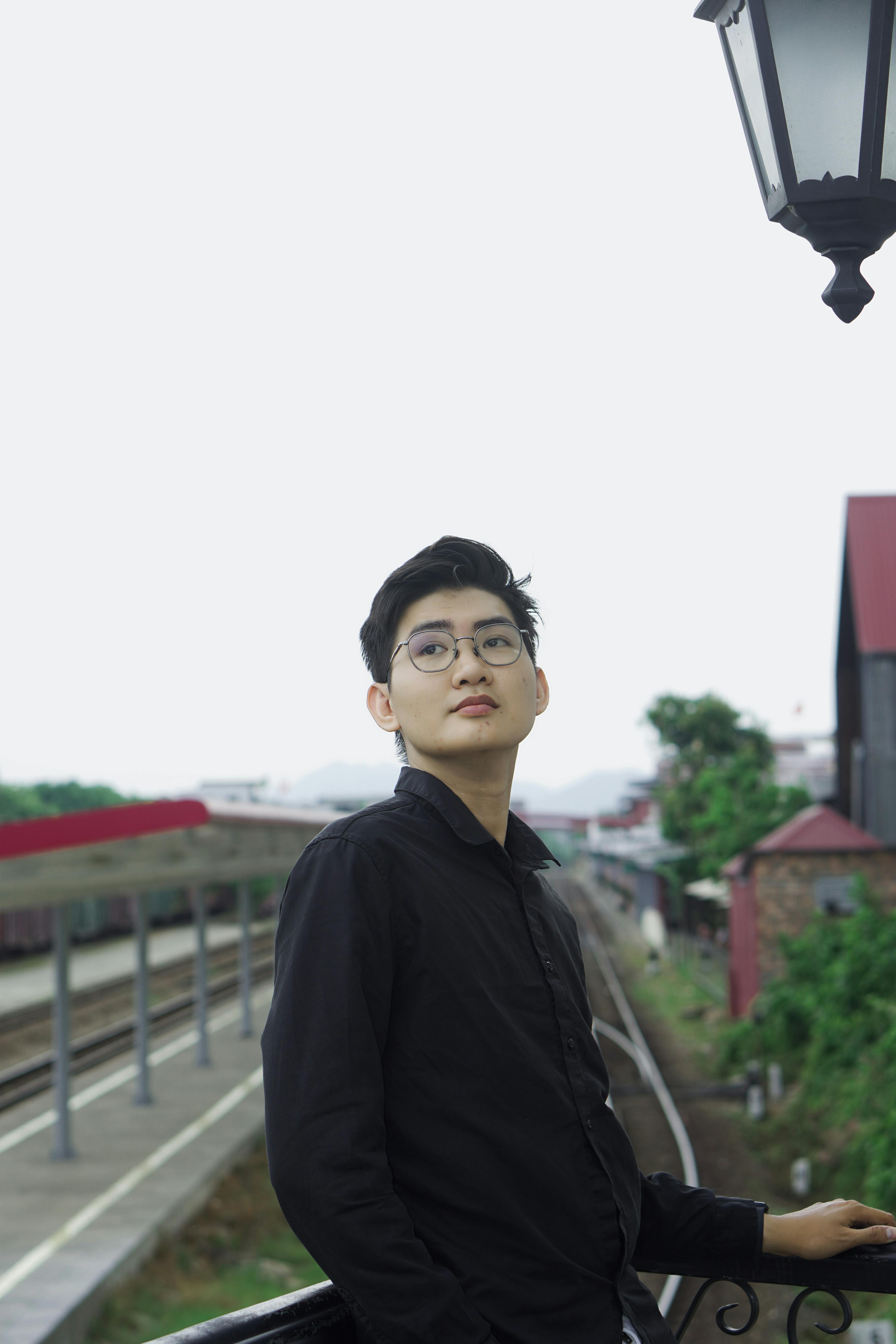 Portrait of a young man in black shirt leaning on a railing at Hue train station in Vietnam.