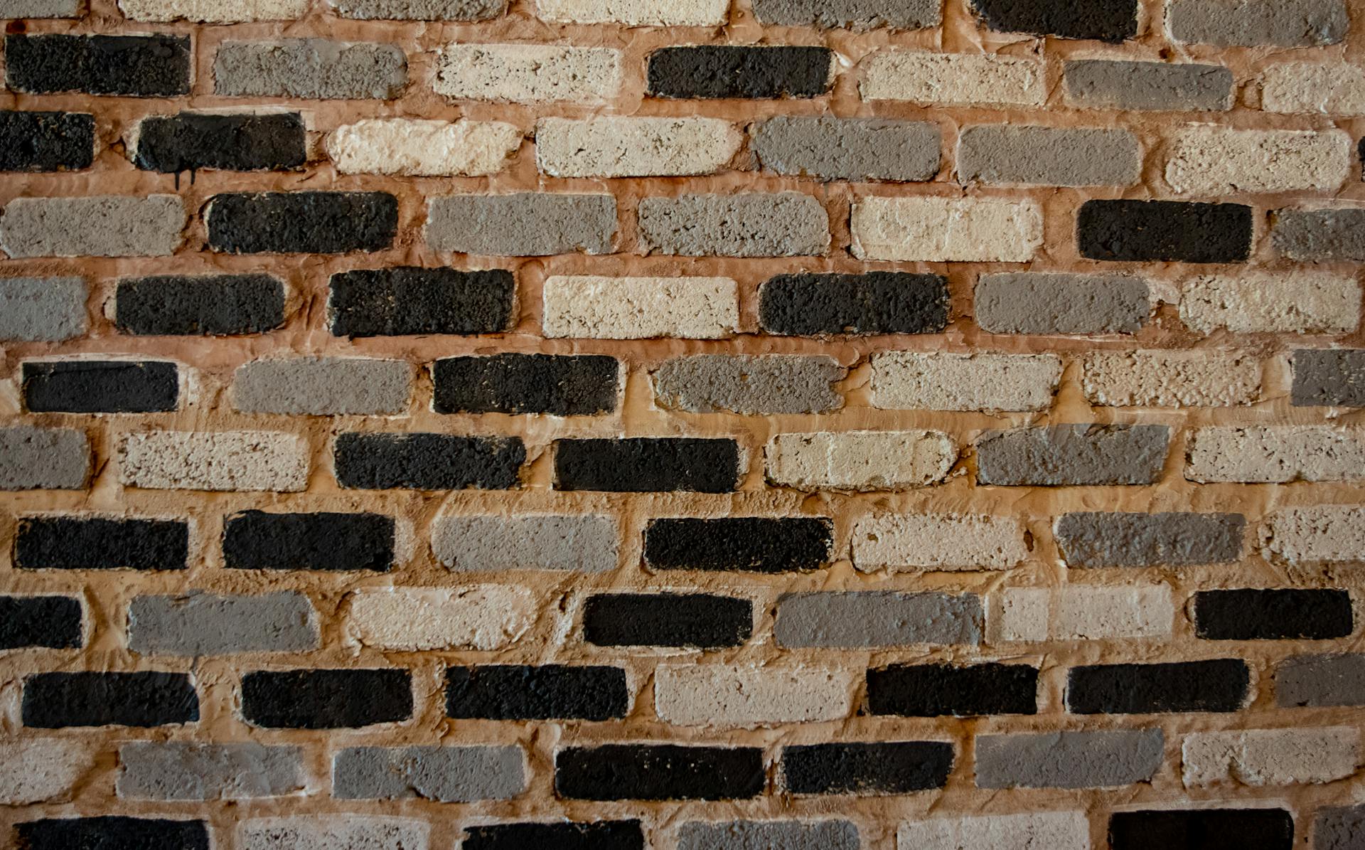 A textured brick wall showcasing varied patterns and tones, perfect for backgrounds and design elements.