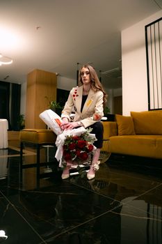 Sophisticated woman holding roses in a chic indoor setting, highlighting elegance and fashion.