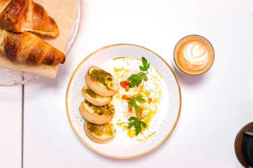 Free Top view of breakfast with croissants, a plate of eggs with parsley, and a cappuccino. Stock Photo