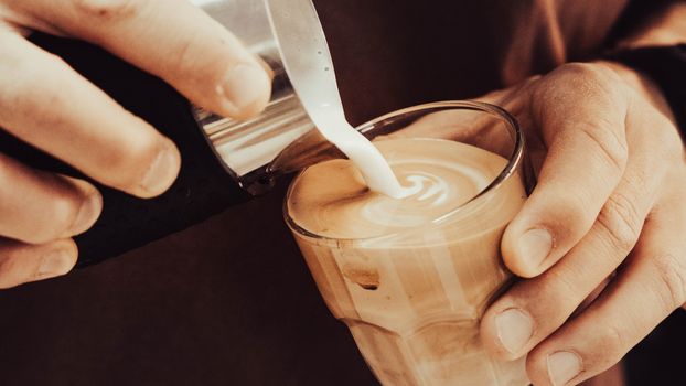 Close-up of a barista pouring milk into a delicious latte, creating latte art.