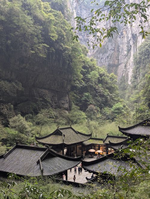 Free Traditional Chinese architecture nestled in a stunning, verdant mountain gorge. Stock Photo