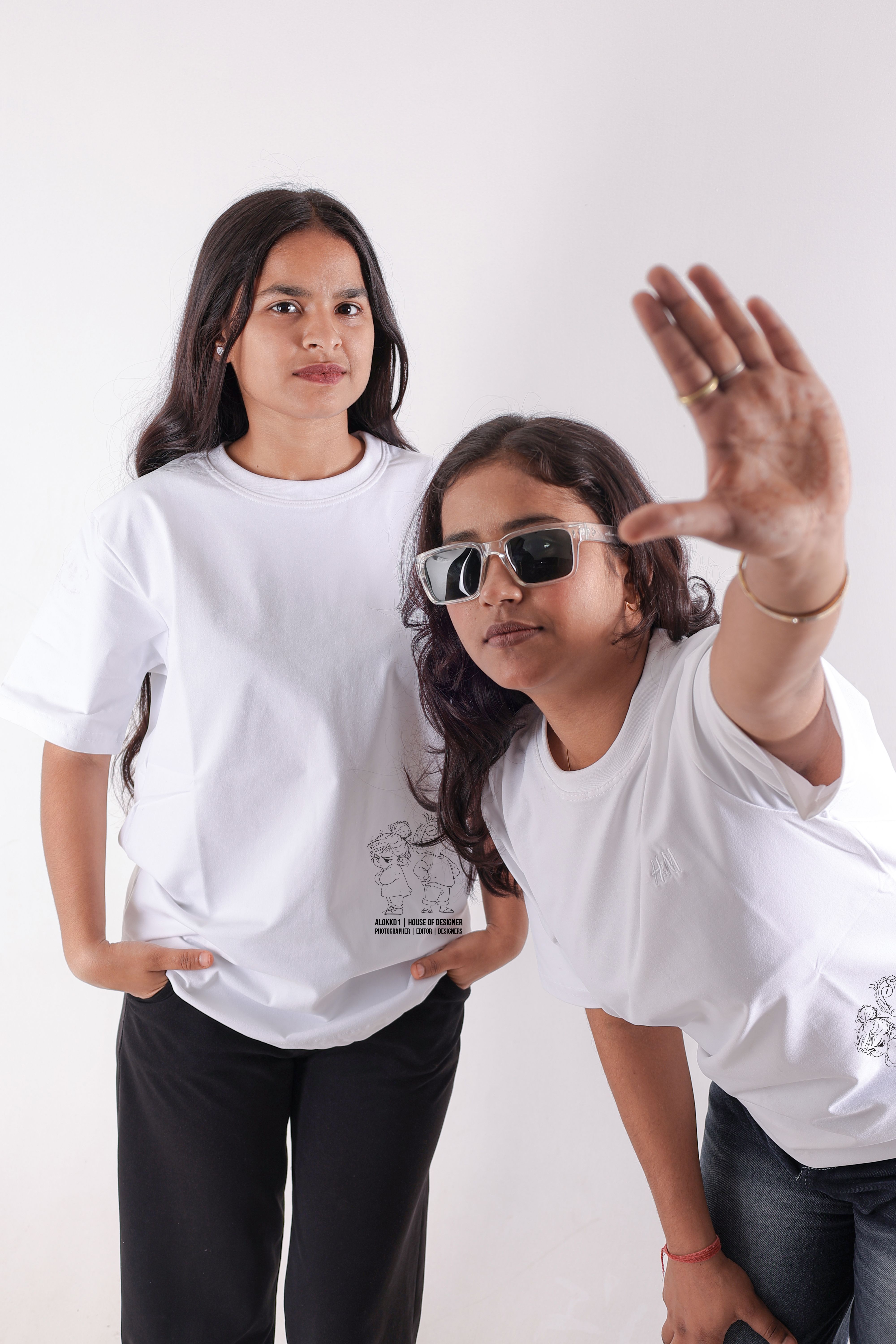 Stylish portrait of two young women in white t-shirts and sunglasses, posing in a studio in New Delhi, India.