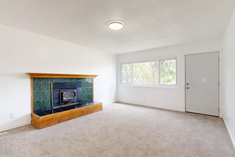 Bright empty living room featuring a modern fireplace and large window view.