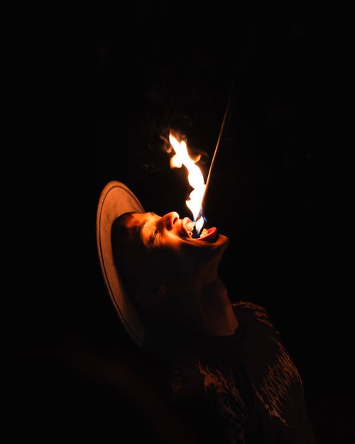 Free A fire eater performs a daring stunt at night, captivating with flames and shadows. Stock Photo