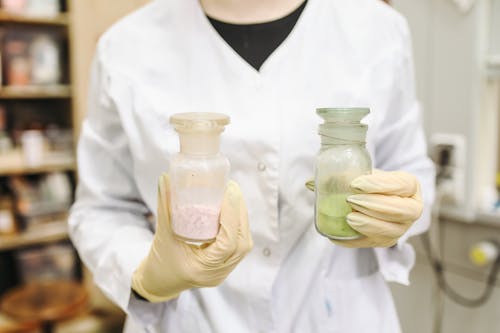 Person In White Button Up Lab Gown Holding Clear Glass Jar