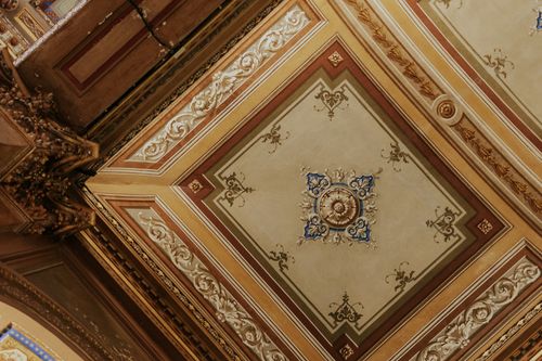 Free A detailed view of a richly decorated Victorian-style ceiling with intricate plasterwork and motifs. Stock Photo