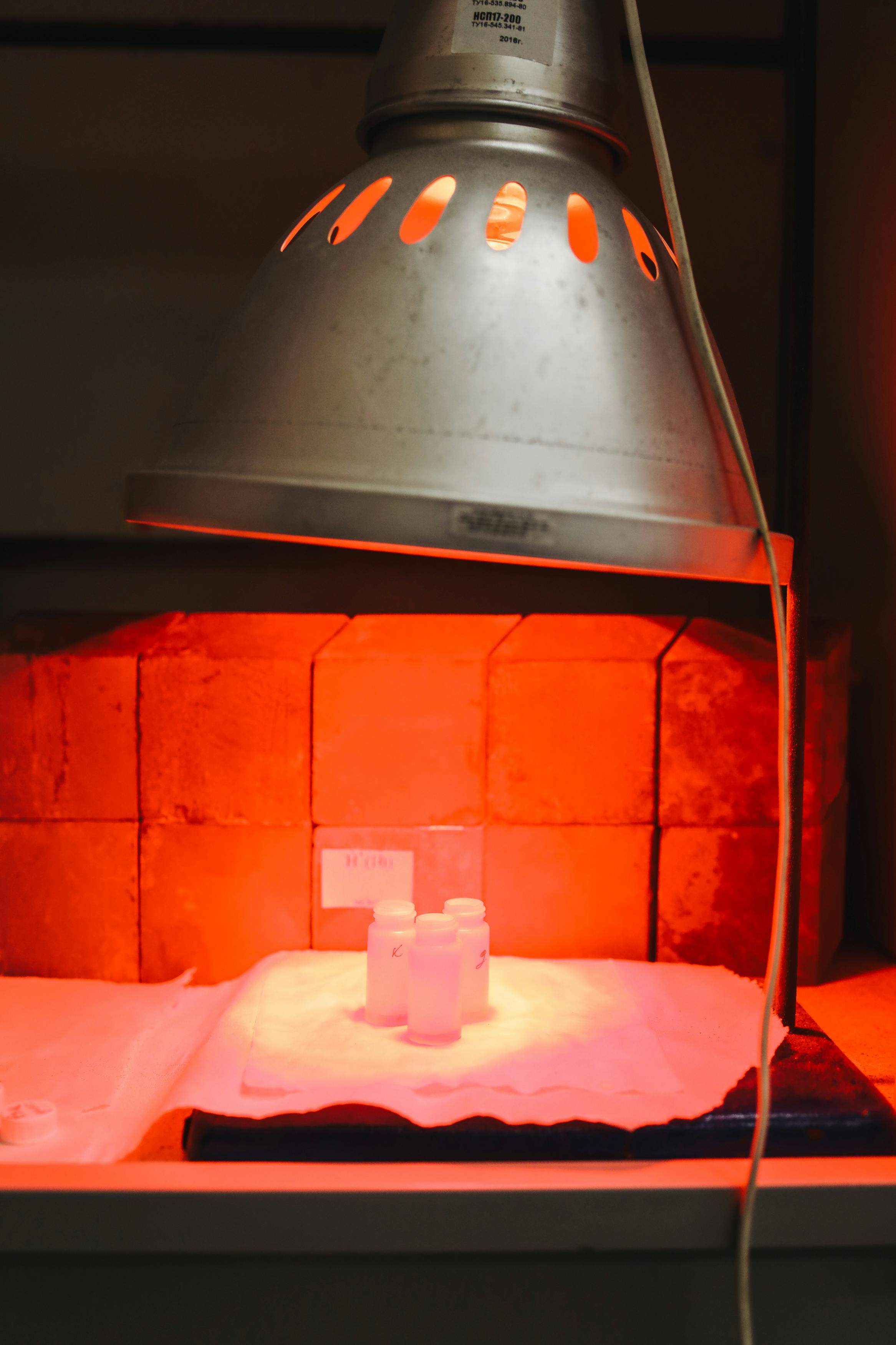 Infrared lamp illuminating test samples in a laboratory setting, highlighting experimental research.