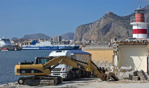 Free Excavator and ferry in busy Palermo harbor with lighthouse backdrop. Stock Photo