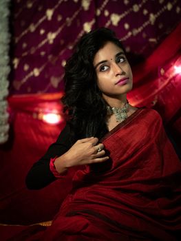 Portrait of a South Asian woman in a red saree, embracing traditional Indian aesthetics.
