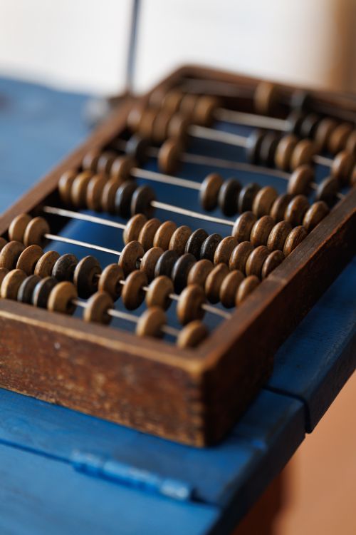 Free A close-up of a classic wooden abacus displaying rows of counting beads on a blue surface. Stock Photo