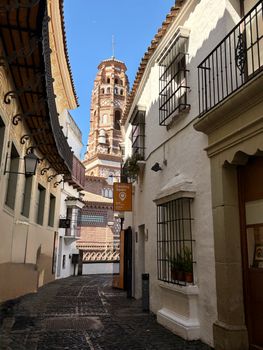Scenic view of a narrow alleyway in Spain, featuring traditional architecture and a historic tower.