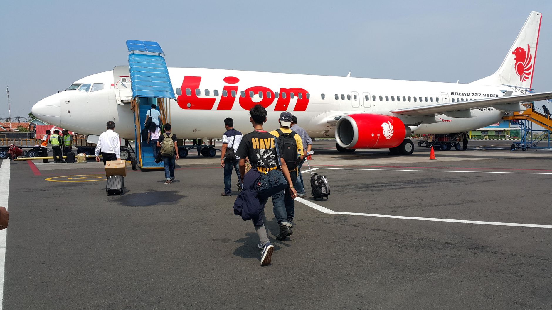 Travelers board a Lion Air flight at an Indonesian airport, preparing for departure.