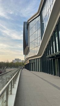 Glass facade of a modern building with curved design, set against a bright sky.