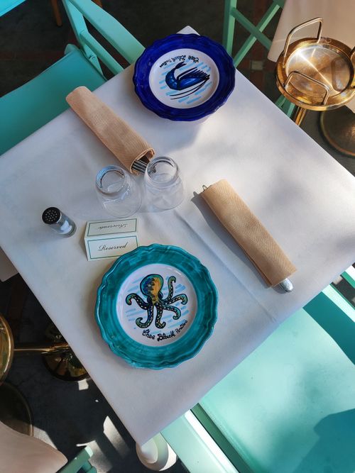 Free A top view of a reserved restaurant table with unique nautical-themed plates and blue chairs. Stock Photo
