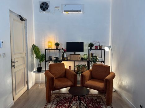 Inviting home office with cozy armchairs, plants, and well-organized shelves.