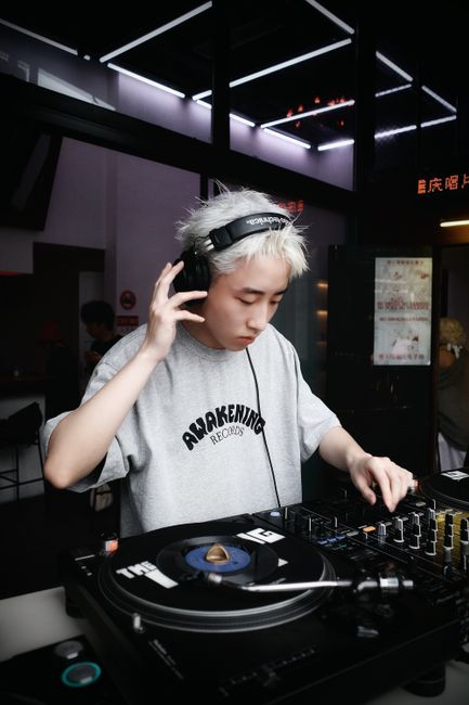 DJ playing music on turntables at a stylish indoor club, creating vibrant beats and lively atmosphere.