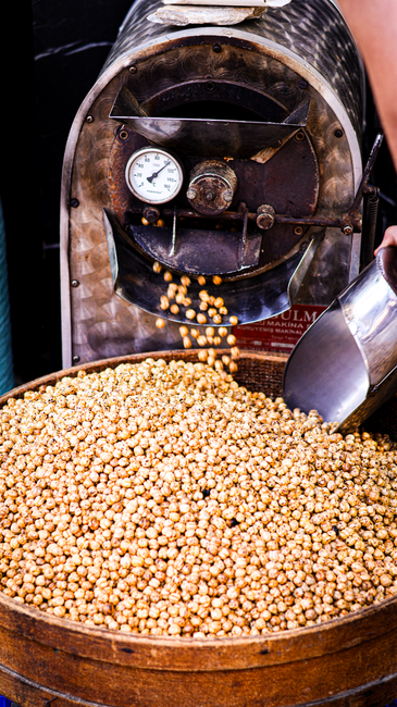 100g Hạt Macca Chứa Bao Nhiêu Calo? Ăn Có Gây Béo Không? 5 A detailed view of a coffee roasting machine in action with beans.