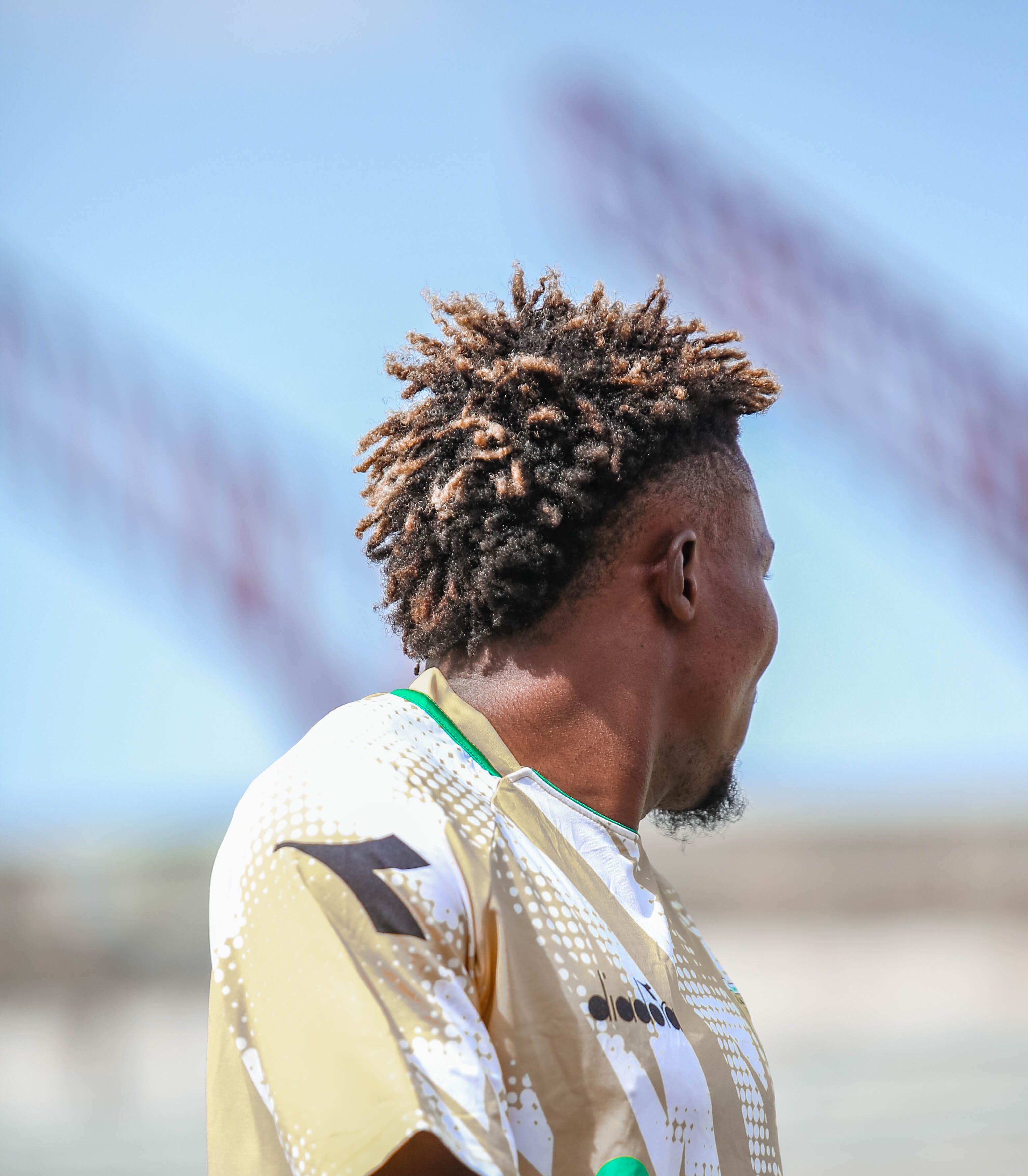 A young African male athlete looking away in an outdoor sports setting on a sunny day.