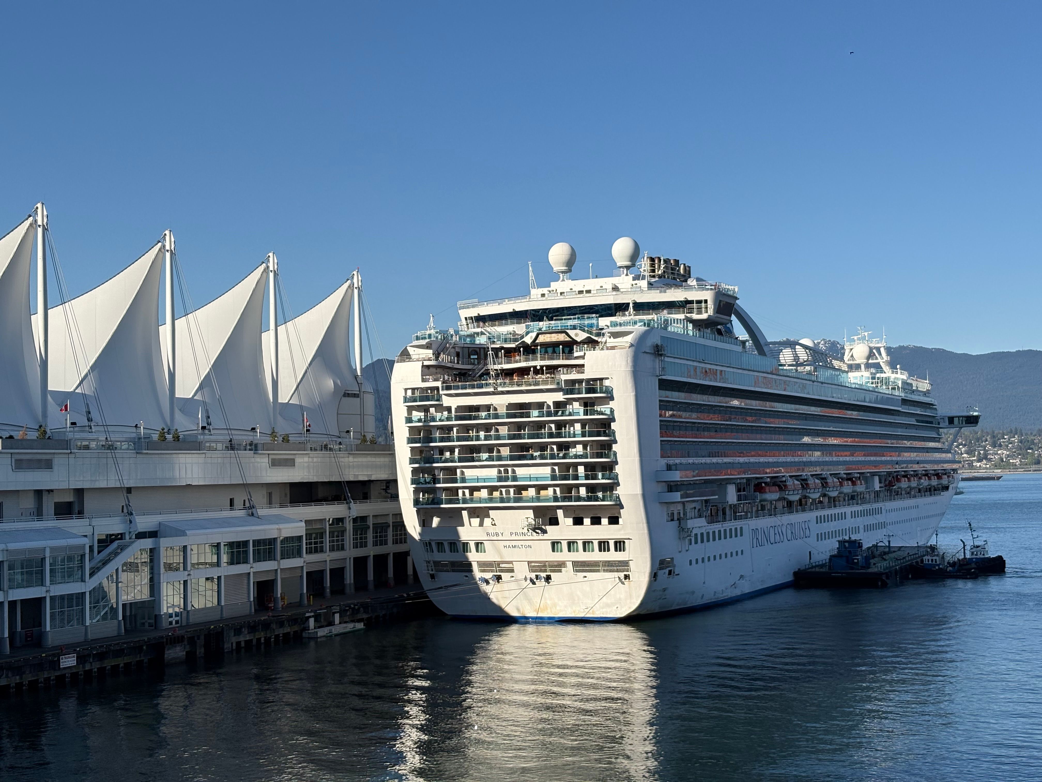 Cruise ship docked at Canada Place in Vancouver, showcasing iconic sails and harbor views.