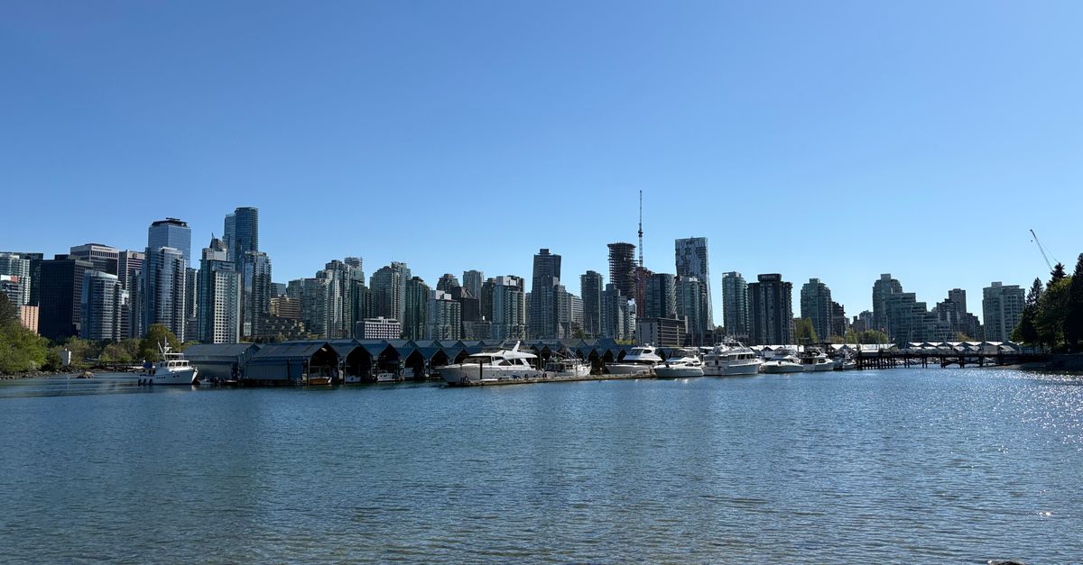 Stunning view of Vancouver's skyline from the waterfront with boats and clear blue sky.