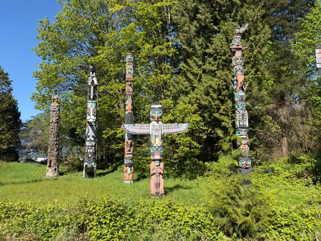 Totem poles in a vibrant forest, Stanley Park, Vancouver, showcasing rich First Nations art.