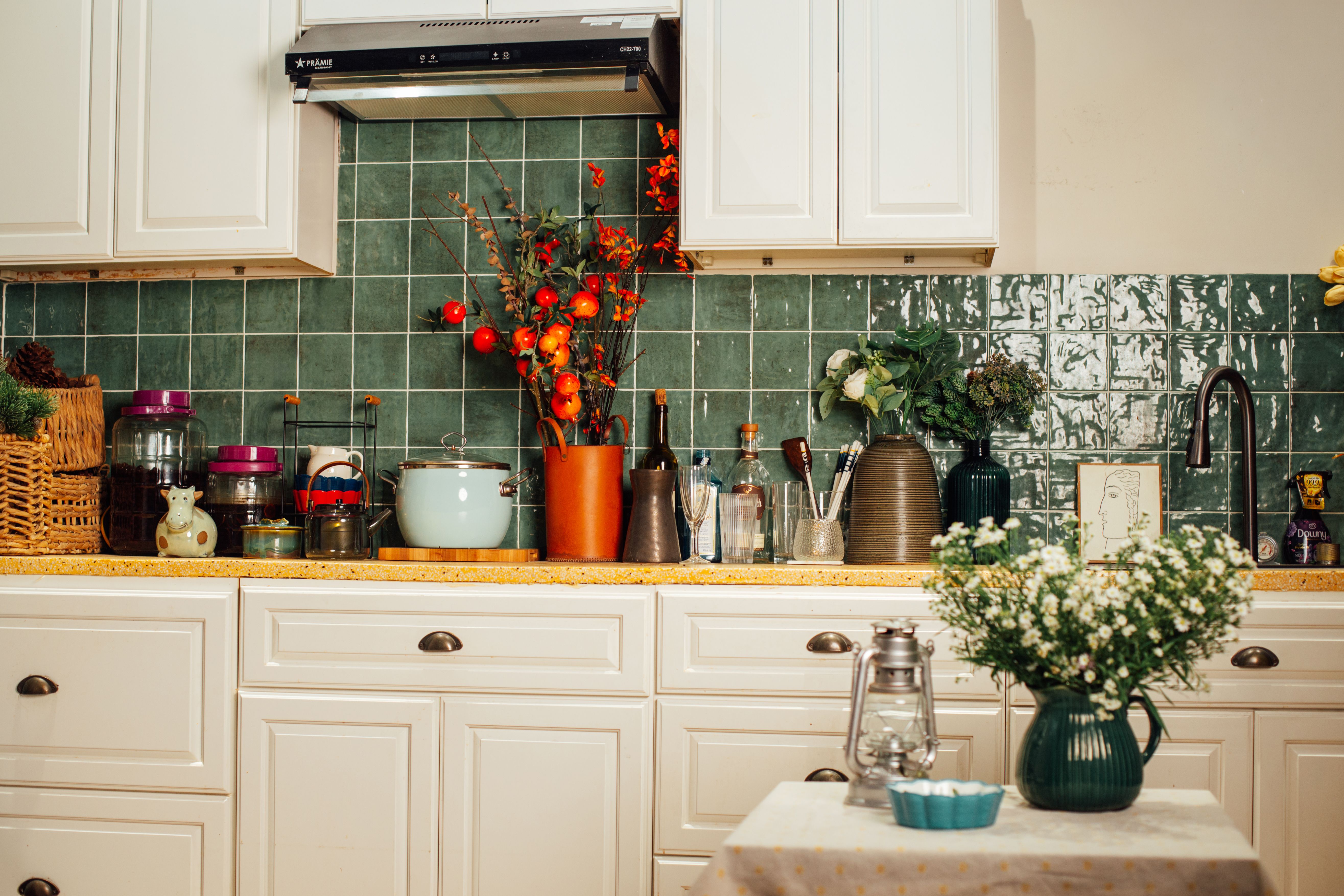 Uma cozinha aconchegante com backsplash de azulejos verdes e diversos utensílios que criam uma atmosfera acolhedora.