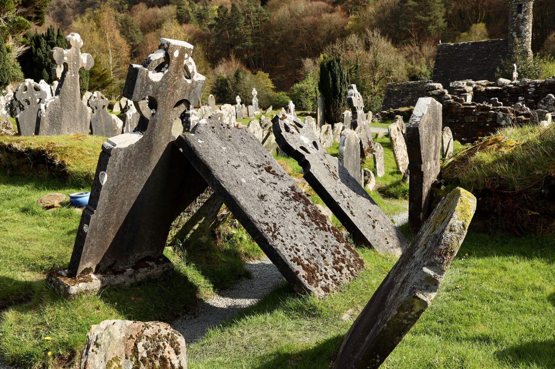 Ancient Celtic gravestones in a green Irish cemetery under a bright sky, showing historical significance.