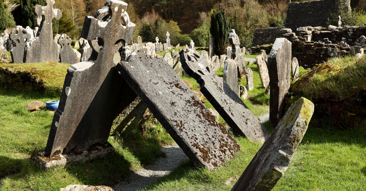 Ancient Celtic gravestones in a green Irish cemetery under a bright sky, showing historical significance.