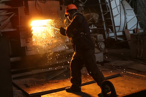 Free Man in Helmet Working with Steel in Furnace Stock Photo