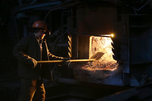 Man in Helmet Holding Shovel ear Furnace