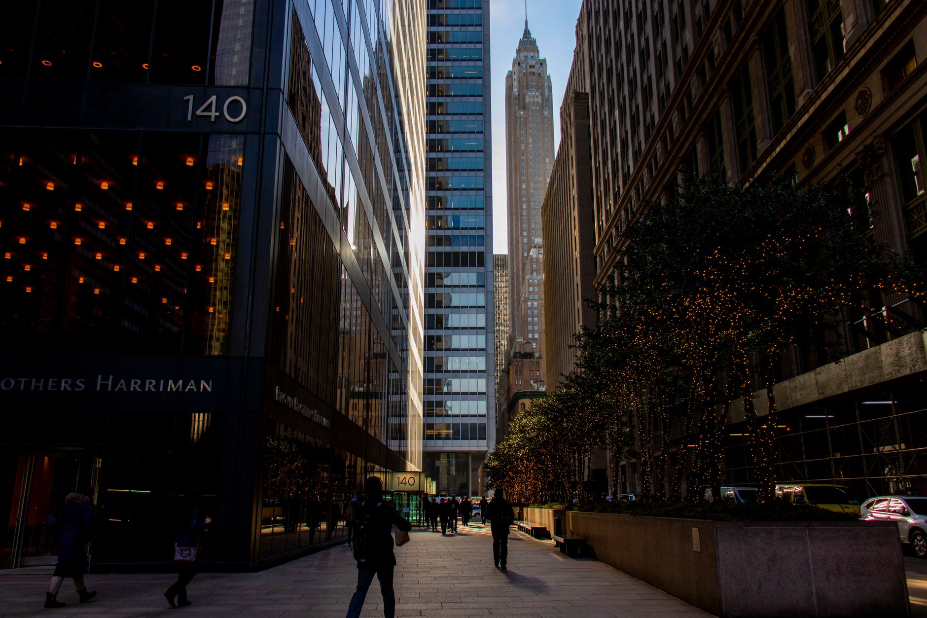 Street view of New York City with towering skyscrapers and festive lights during the day.