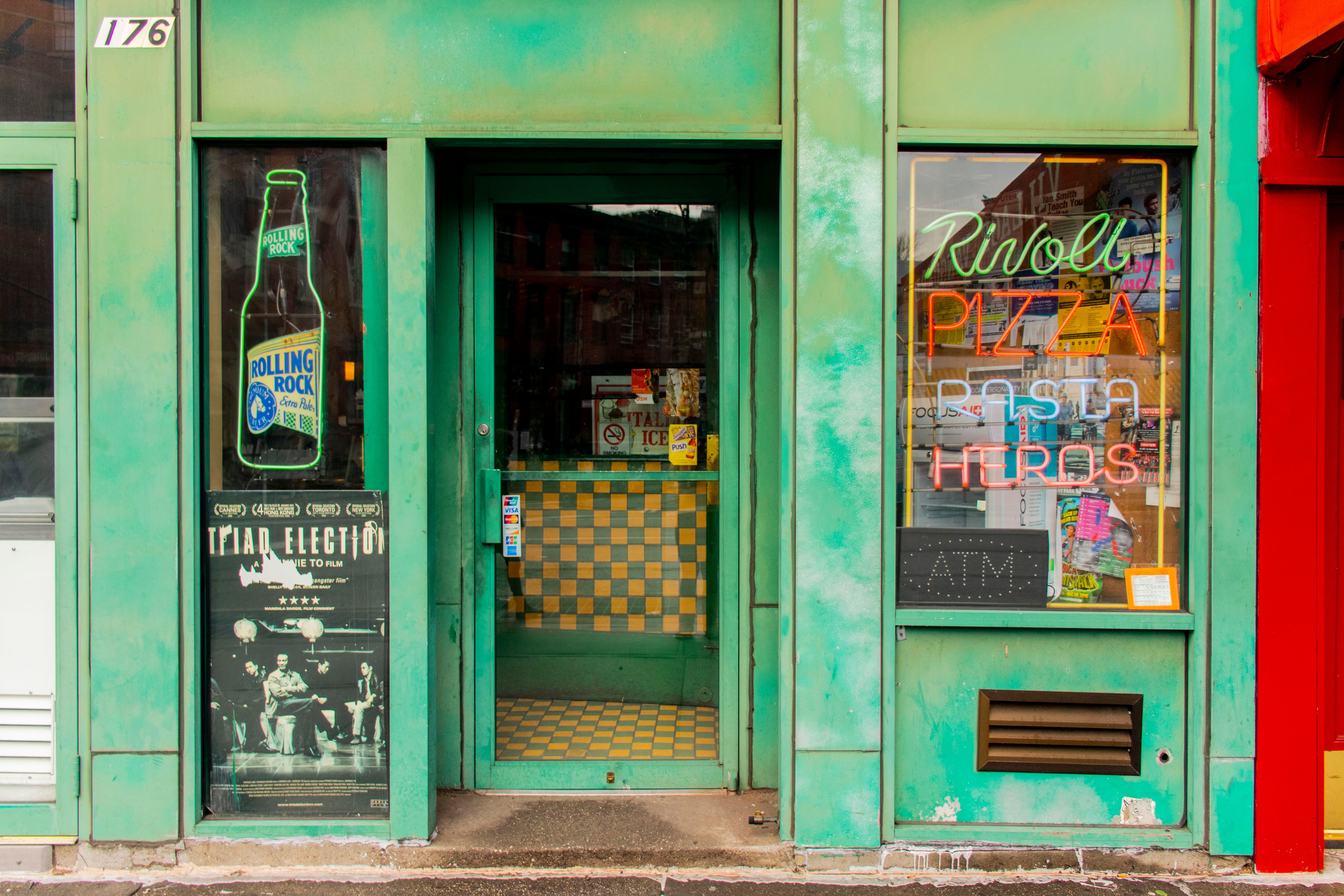 Bright facade of a New York pizza restaurant with neon signs and vintage accents.