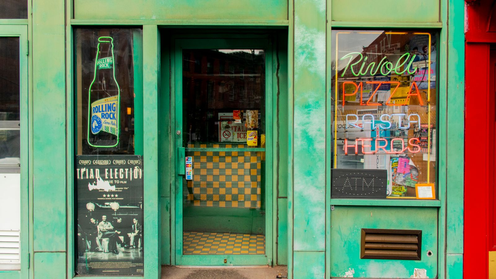 Bright facade of a New York pizza restaurant with neon signs and vintage accents.