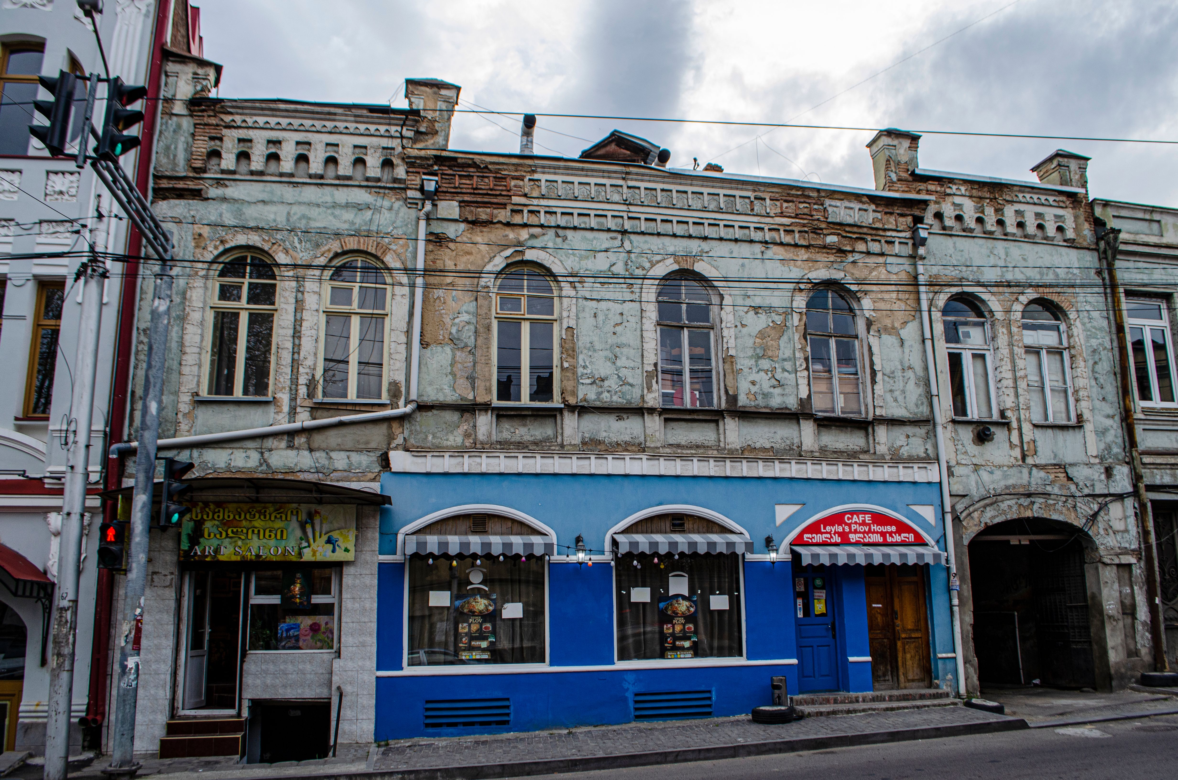 Old building facade with a cafe in Tbilisi, showcasing vintage architecture.