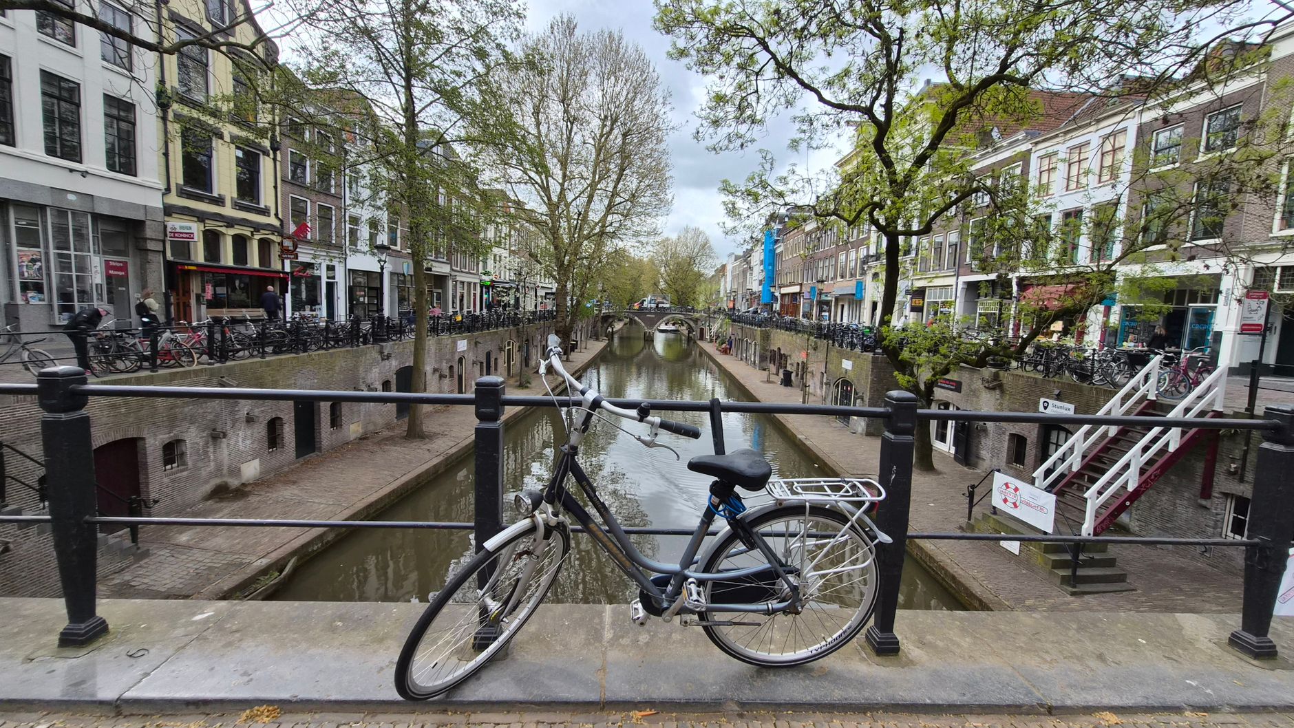 Scenic view of a bicycle parked on a bridge over the historic Oudegracht canal in Utrecht, Netherlands.