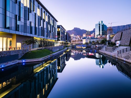 Free Stunning view of modern buildings reflecting on a canal in Cape Town at twilight. Stock Photo