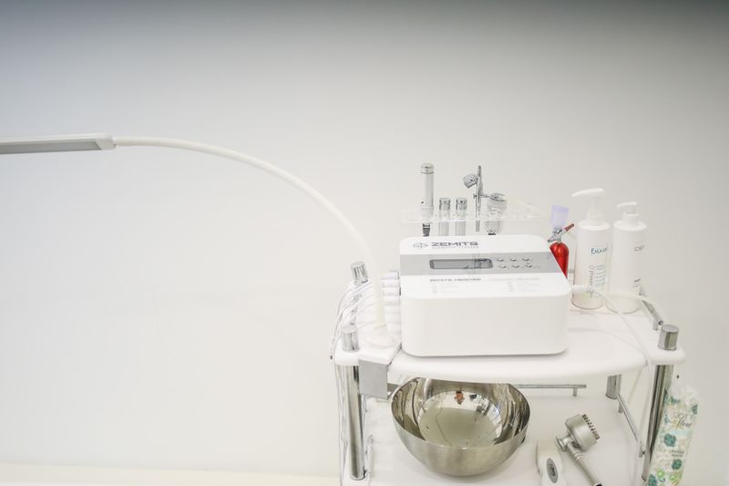 Multifunction esthetics unit on a rolling stand, probe handpieces upright in their holders