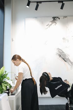 A hair stylist performing a treatment on a reclining client at a modern salon.