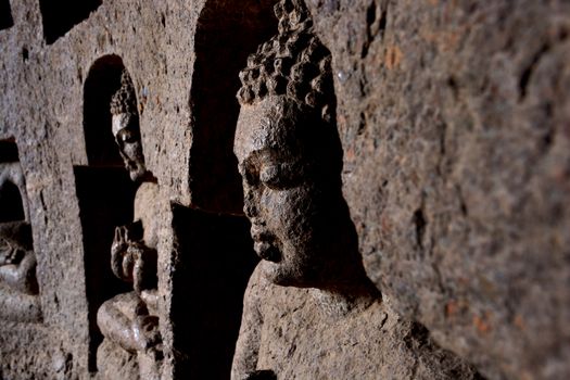 Side view of ancient rock-cut Buddha sculptures carved into a cave wall, capturing the serene expressions and intricate details.