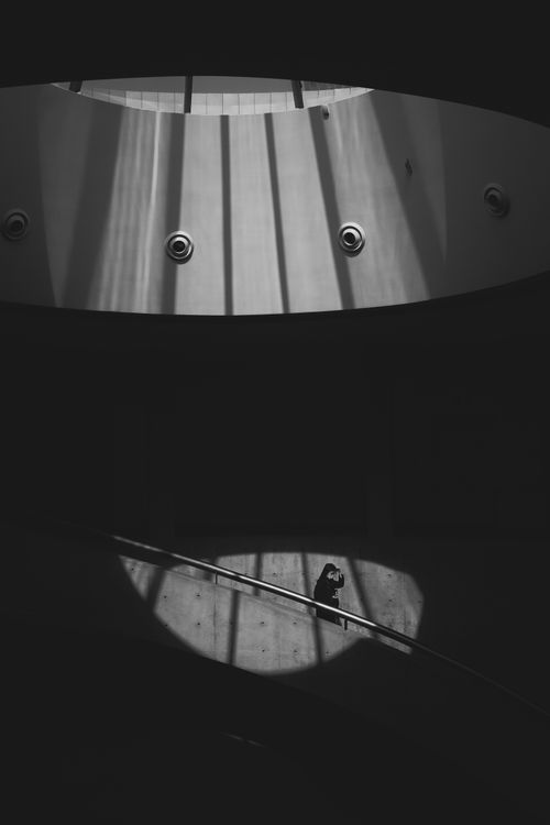 Free A lone figure stands on a curved ramp with striking light and shadow contrasts in an architectural setting. Stock Photo
