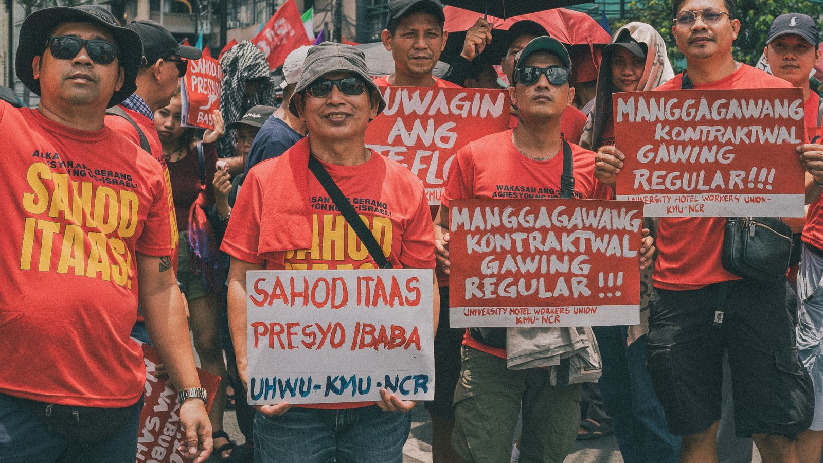 A group of adults protesting for regularization and higher wages in Manila.