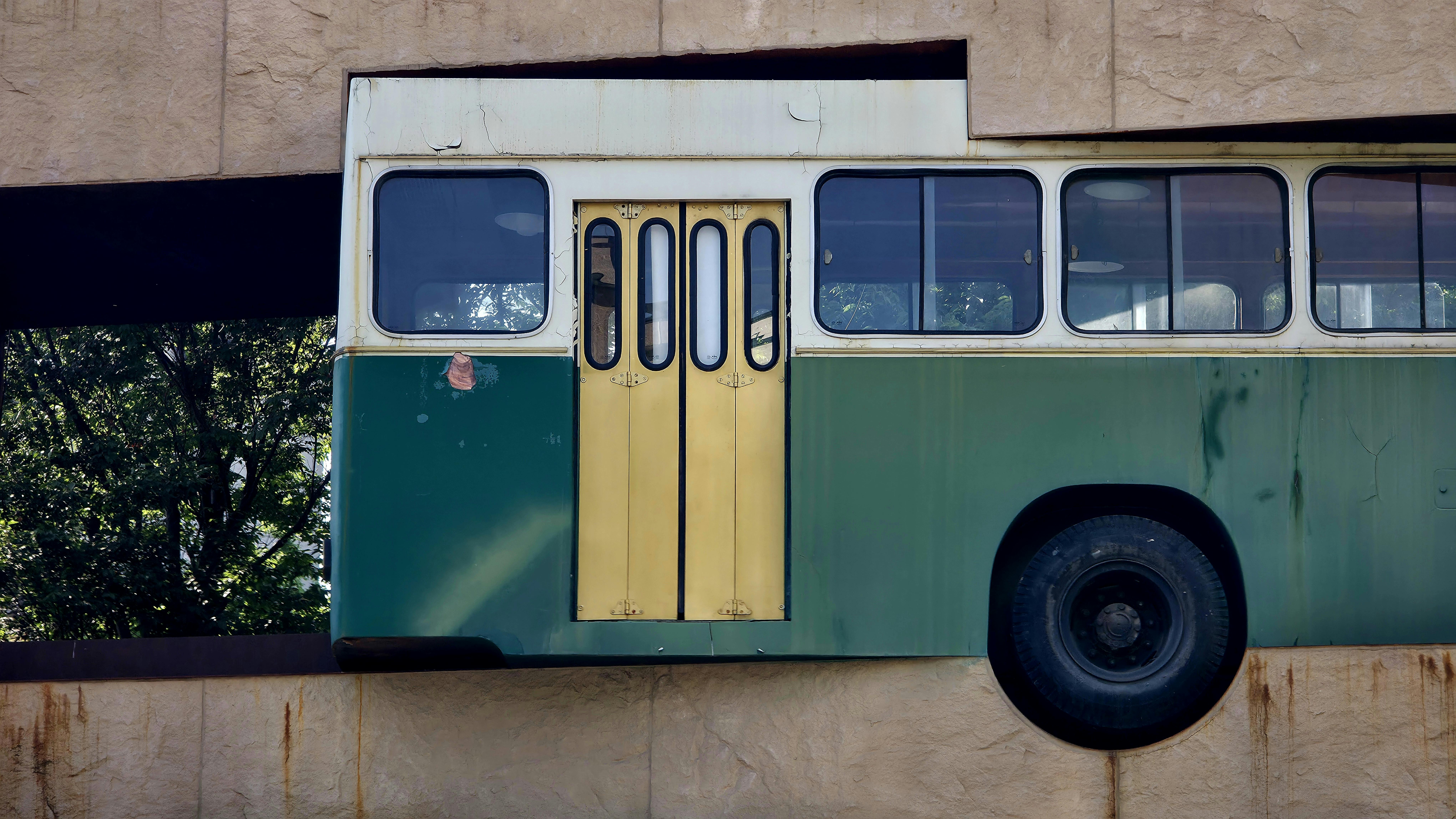 Installation artistique créative représentant un bus rétro émergeant du mur d'un bâtiment, captivant l'attention par son design surréaliste.