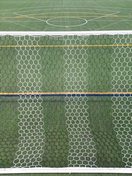 Aerial view of a soccer field with a focus on the goal net and turf symmetry.