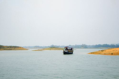 Free Traditional boat sailing on serene waters surrounded by scenic landscapes in Sylhet, Bangladesh. Stock Photo