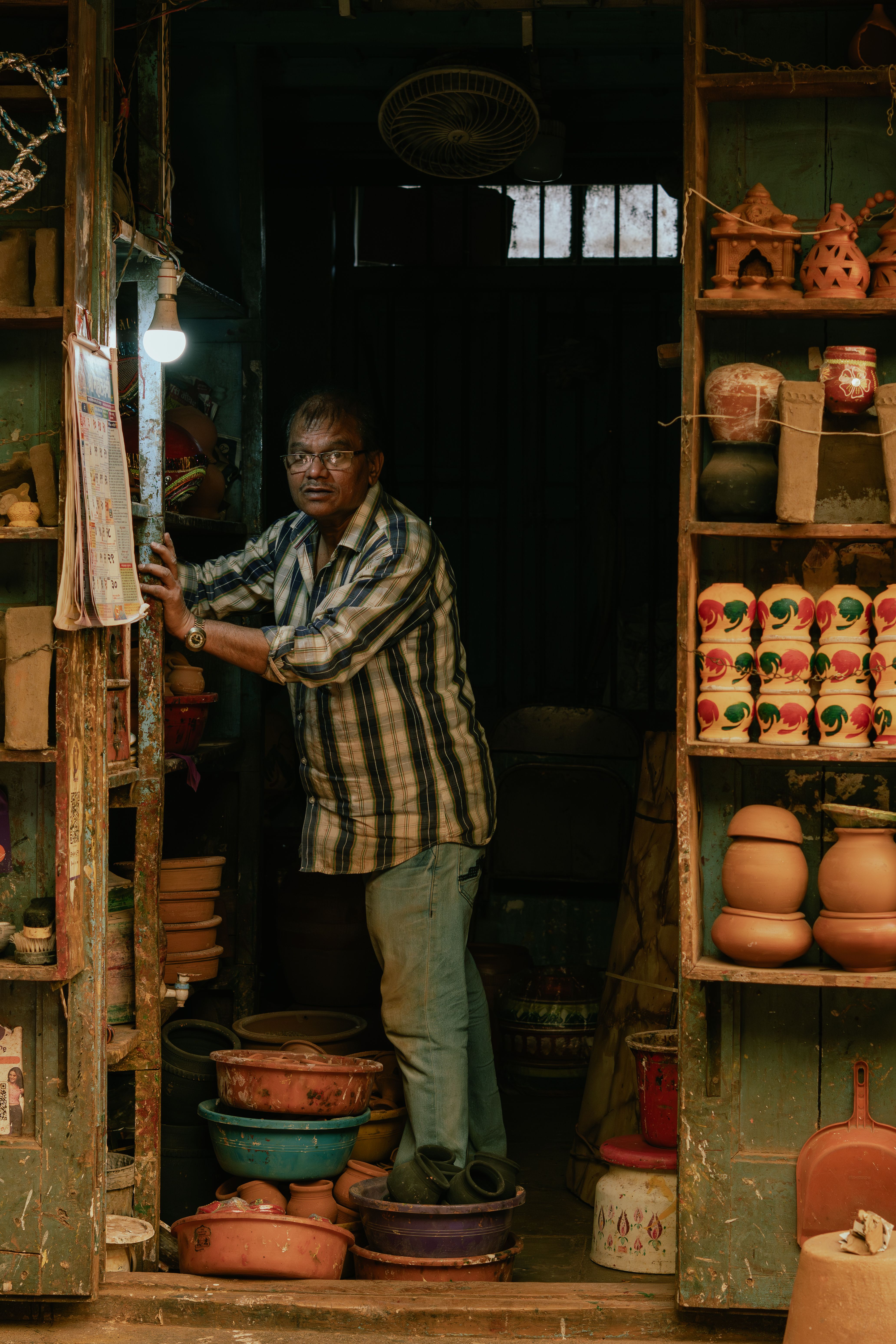 Man in pottery shop in Pune, Maharashtra, showcasing traditional arts and crafts.