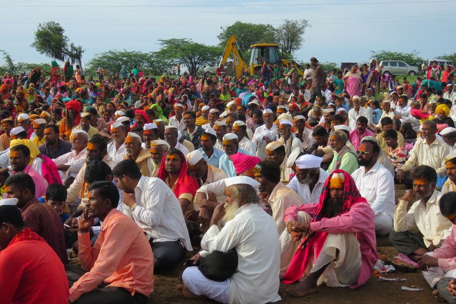 Vibrant outdoor gathering of people in cultural attire with a natural backdrop.
