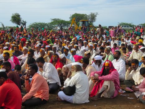 Vibrant outdoor gathering of people in cultural attire with a natural backdrop.