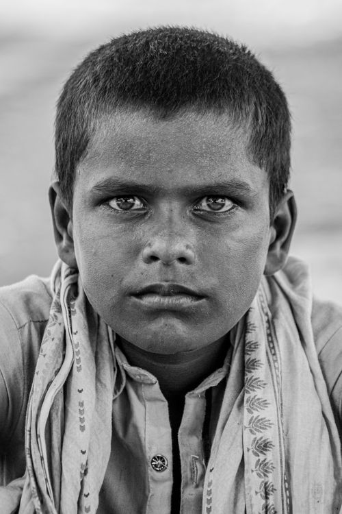 Free A compelling black and white portrait of a young boy from Sindh, Pakistan showcasing his intense gaze. Stock Photo